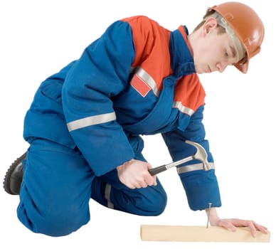 The man in a uniform hammers in a nail into a board