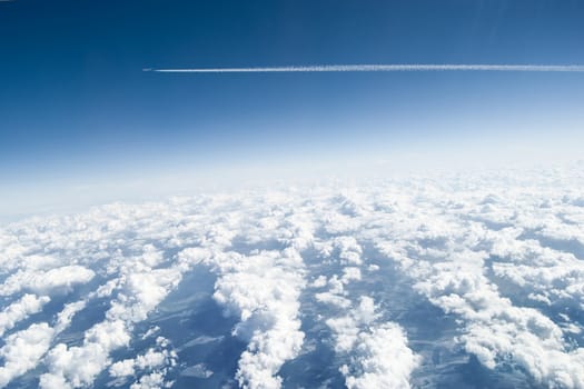 View from above the clouds with an airplane passing by