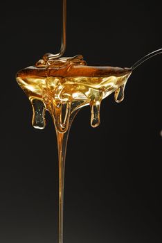 Golden honey spilling over black background stock photo