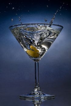 Martini cocktail splash with an olive close view