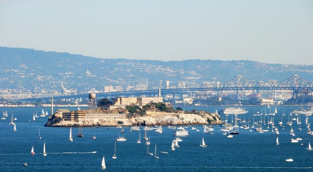 Alcatraz Island and Prison in San Francisco Bay on a sunny and hazy day with many boats around