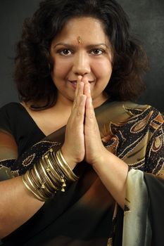 A beautiful Indian woman wearing a traditional sari and praying.
