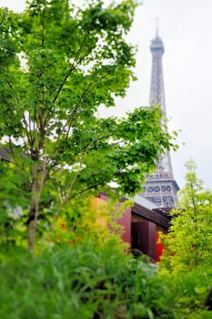 Eiffel Tower through the leaves of trees in Paris. Photo with tilt-shift effect