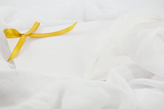 blank note, yellow ribbon and feather to write over white fabric