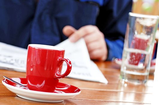 man reading newspaper drinking coffee and water