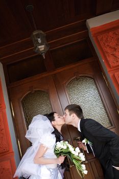 kiss of bride and groom near the door