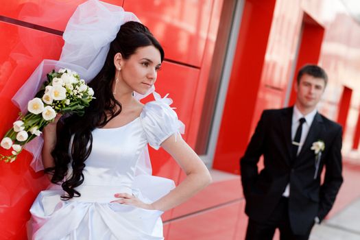 bride and groom by the red wall