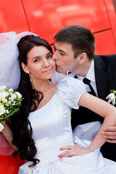 bride and groom by the red wall