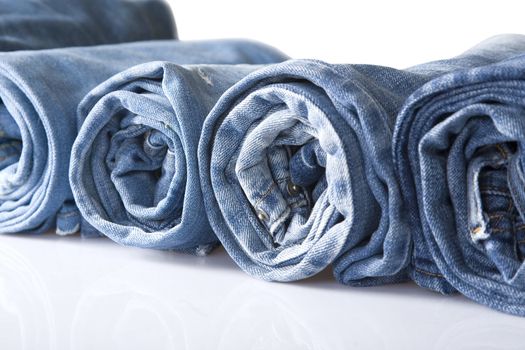 roll blue denim jeans arranged in line, isolated on white