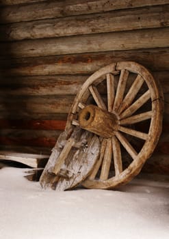 Wheel of cart on the barn near wooden wall