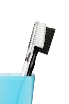 Black and white toothbrushes in blue glass. Isolated with clipping path