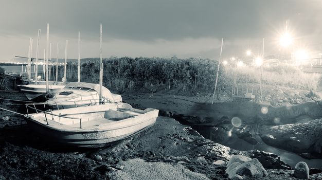 City scenery of discard boats on silt of river in night.