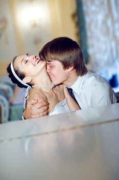 happy bride and groom kiss at the piano