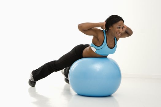 African American young adult woman working out with exercise ball.