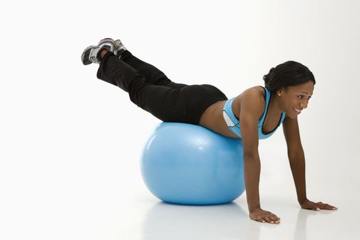 African American young adult woman working out with exercise ball.