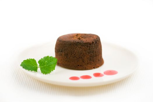 chocolate fondant with peppermint leaves and drops of strawberry sauce