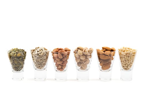 coctail of different nuts in short glasses, shot on white