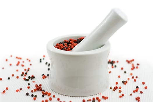 mortar and pestle crushing pepper, with pepper spread around