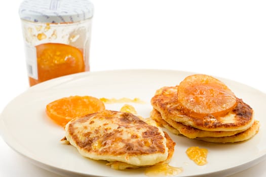 small cottage pancakes with some orange jam, jam jar in background, isolated on white