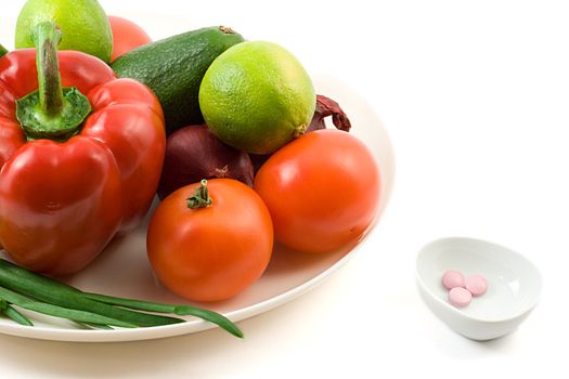 group of vegetables and vitamin pills, shot on white