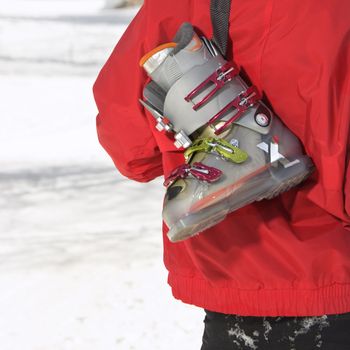 Close up of ski boot hung over shoulder of shoulder of male teenager.