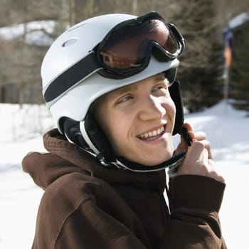 Caucasian male teenager fastening helmet.