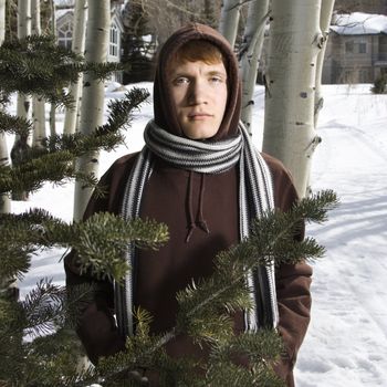 Portrait of a Caucasian male teenager wearing hoodie and scarf in winter setting.