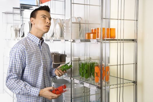 Asian male shopping for dishes and glasses in retail store.