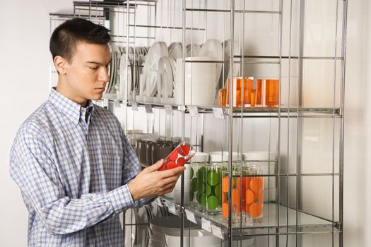 Asian male shopping for dishes and glasses in retail store.