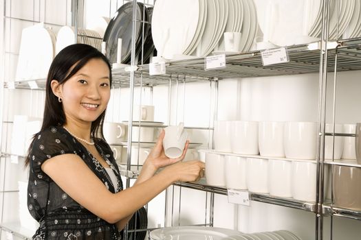 Asian female shopping for dishes and glasses in retail store.