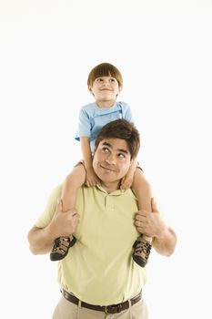 Father holding son on shoulders standing against white background.