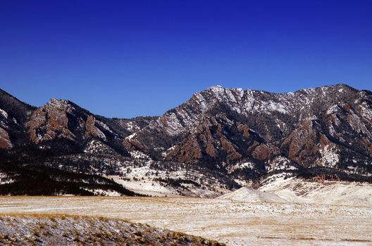 Boulder Colorado's  Flatiron Mountains against blue sky witha dusting of snow