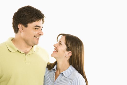 Portrait of smiling couple looking at eachother against white background.