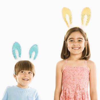 Portrait of boy and girl wearing rabbit ears smiling.