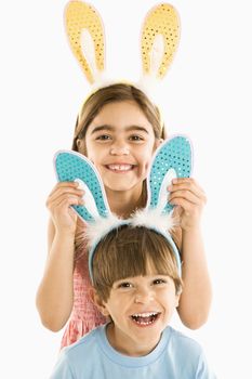 Portrait of boy and girl wearing rabbit ears smiling.