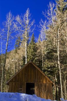 A historical wooden cabin in Colorao sits among winter snow