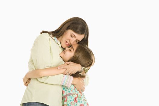 Mother and daughter embracing standing against white background.