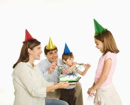 Family celebrating girl's birthday with cake.