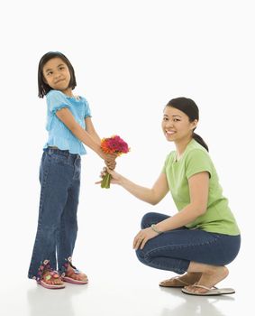 Asian girl handing bouquet of flowers to her mother.