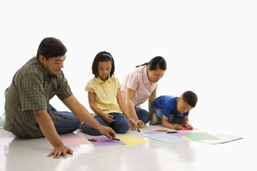 Asian parents sitting on floor with children coloring.