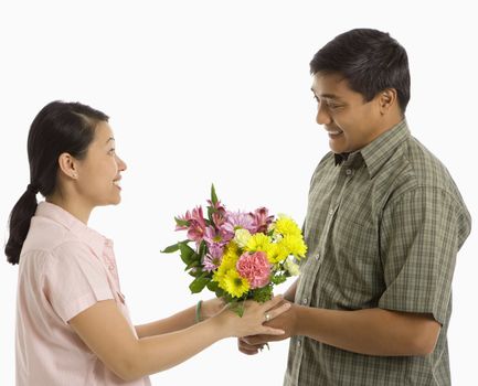 Asian man giving Asian woman a bouquet of flowers.