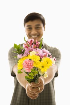 Mid adult Asian man holding bouquet of flowers and smiling.