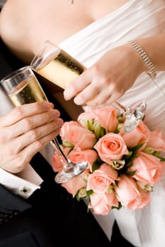 bride and groom with glasses of champagne and red rose bouquet