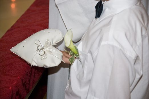 a boy holding the rings for the ring exchange at a wedding ceremony