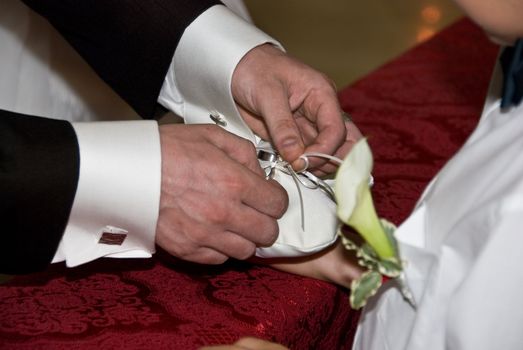 the groom taking the ring off for exchange at a wedding ceremony