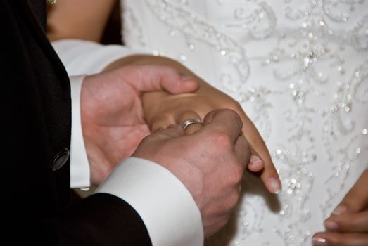 the groom attaching the ring to the brides finger at a wedding ceremony