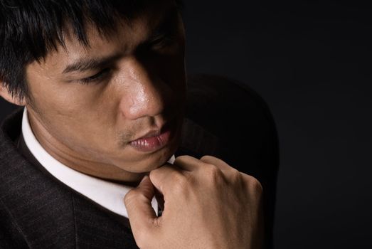 Portrait of young business man thinking in dark.