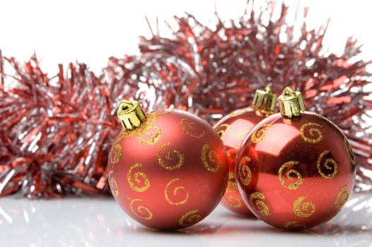 Three red christmas balls with shiny red tinsel