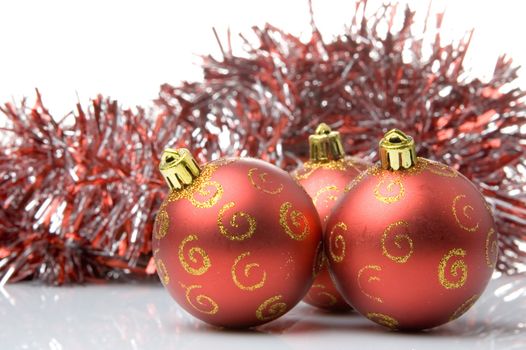 Three red christmas balls with shiny red tinsel