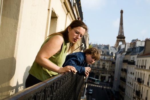 Mother and her son on balcony looking at Paris city life. Eiffel tower in background